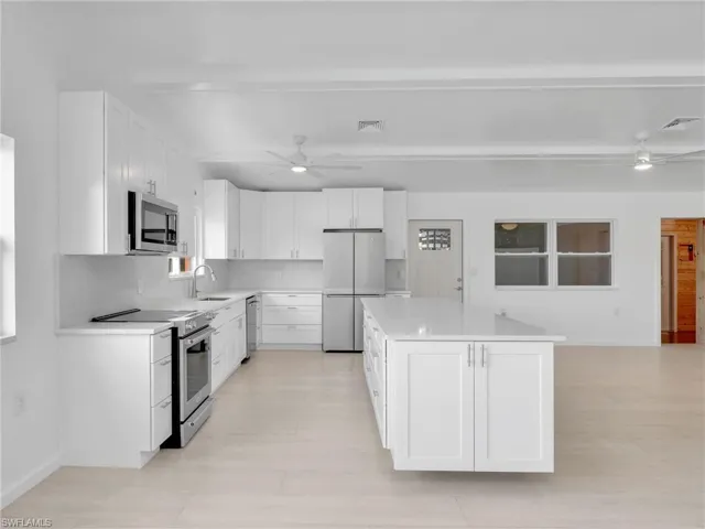 Kitchen with a center island, white cabinets, sink, appliances with stainless steel finishes, and tasteful backsplash
