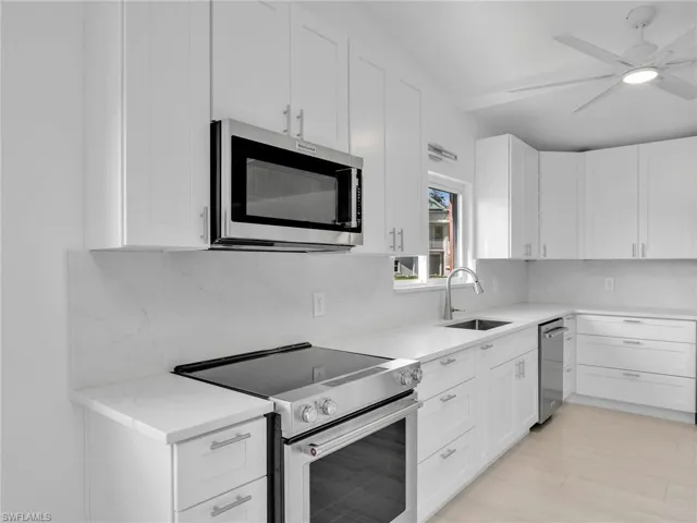 Kitchen with white cabinets, sink, ceiling fan, decorative backsplash, and appliances with stainless steel finishes