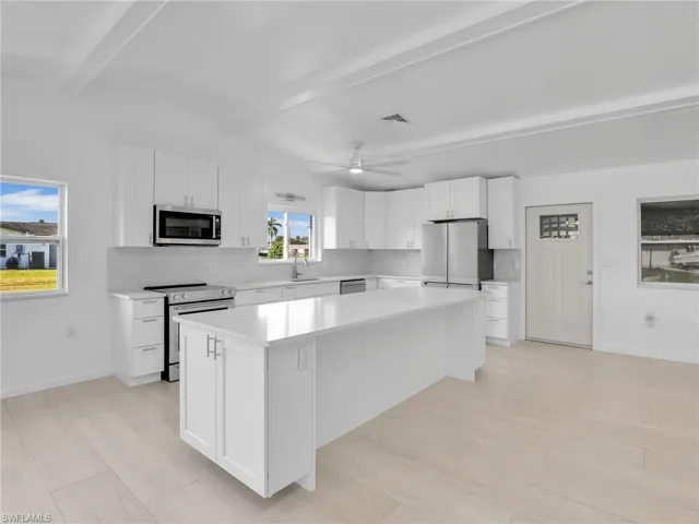 Kitchen with white cabinetry, sink, a kitchen island, and appliances with stainless steel finishes