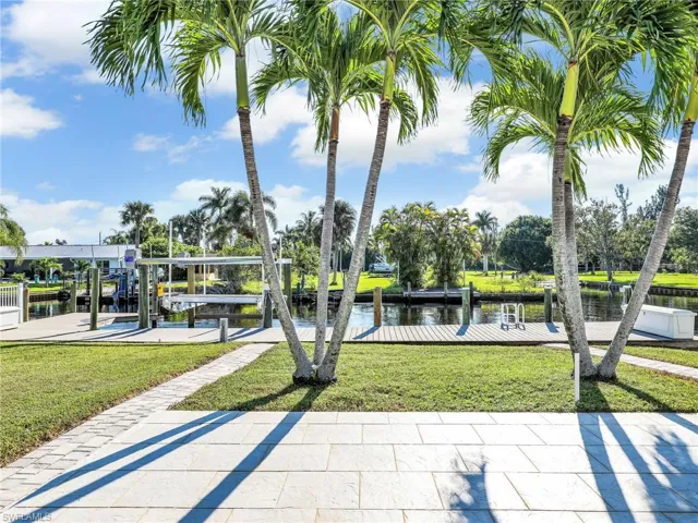 View of property's community featuring a boat dock, a water view, and a lawn