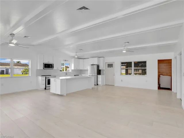 Unfurnished living room featuring vaulted ceiling with beams and light hardwood / wood-style floors