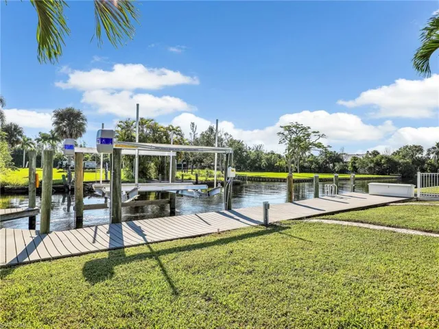 View of dock with a water view and a lawn