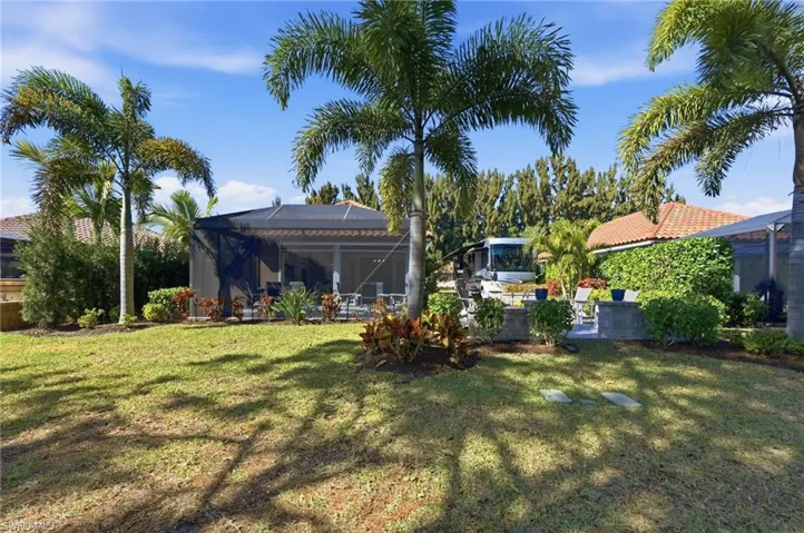 View of grassy yard with a lanai and a patio