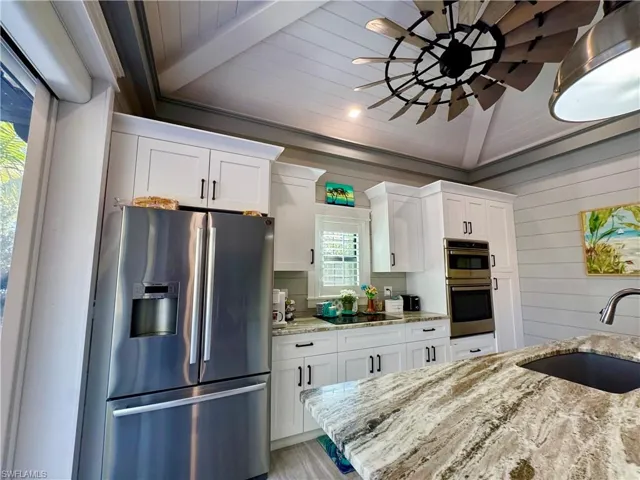 Kitchen with ceiling fan, a kitchen breakfast bar, light wood-style floors, a center island, and hanging light fixtures