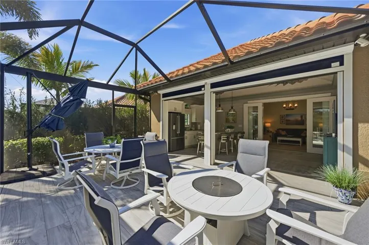 View of patio with outdoor dining space, a sunroom, and glass enclosure