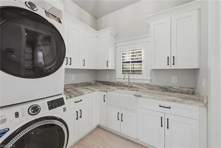 Laundry area with cabinet space and stacked washer and clothes dryer