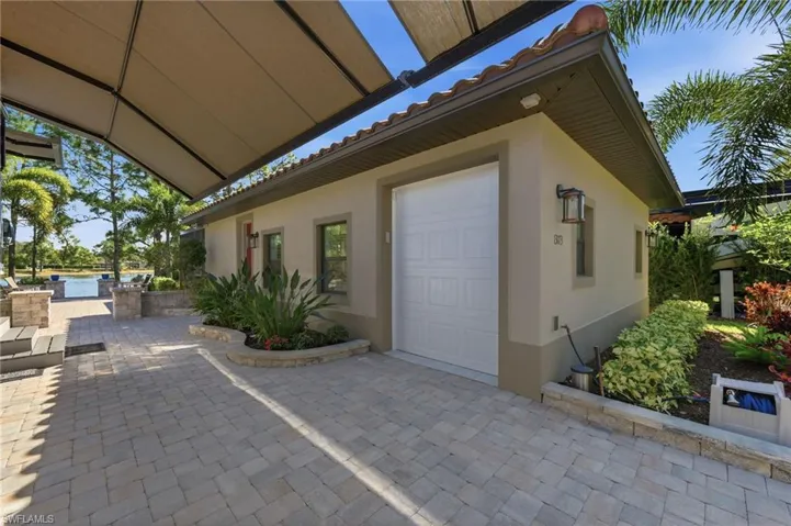 View of exterior entry with a tiled roof, stucco siding, a patio area, and an attached garage