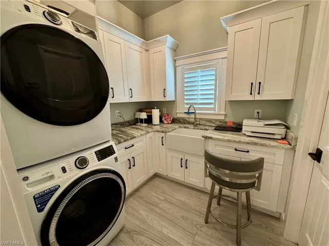 Kitchen featuring light stone counters, hanging light fixtures, white cabinetry, stainless steel appliances, and wood walls