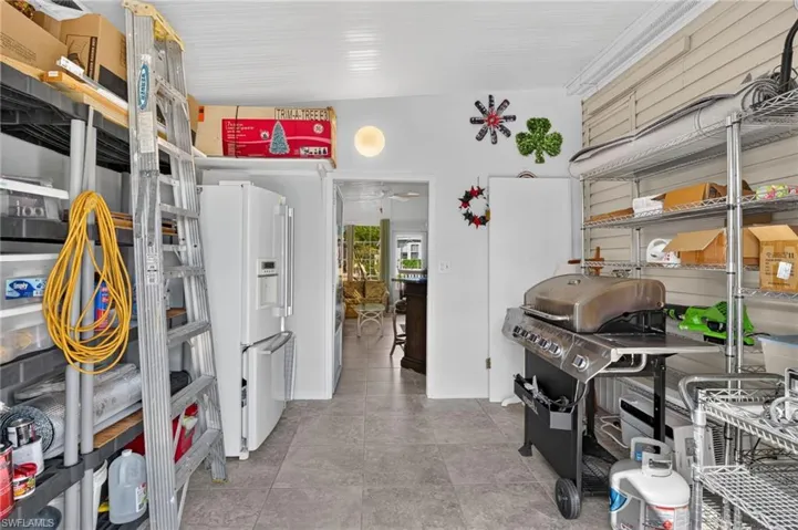 Utility space featuring large-format tile flooring, beaded board ceiling, and wall-mounted slatted storage paneling