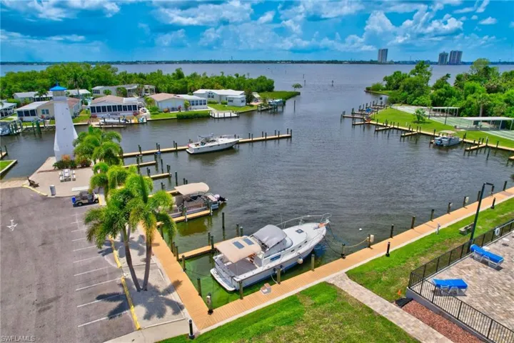 Waterfront community featuring a deep-water boat slip, decorative lighthouse, paved parking area, and manicured landscaping