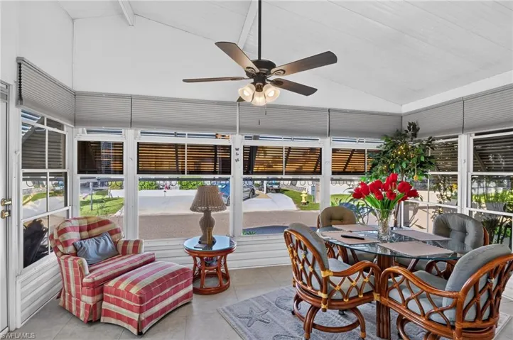 Enclosed porch featuring vaulted ceilings, floor-to-ceiling windows, and a central ceiling fan with integrated lighting