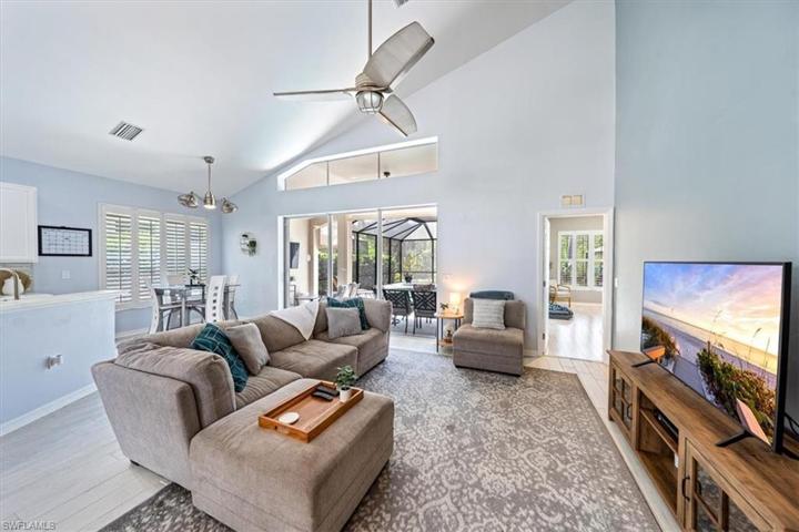 The great room enjoys views of the outdoor living area to the left, open foyer and catwalk to the right, and soaring high ceilings.