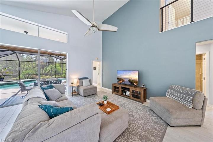 The great room enjoys views of the outdoor living area to the left, open foyer and catwalk to the right, and soaring high ceilings.