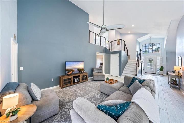 The great room enjoys views of the outdoor living area to the left, open foyer and catwalk to the right, and soaring high ceilings.