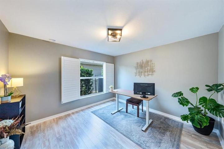 The downstairs guest room (currently used as a home office) features wood look tile flooring and plantation shutters.