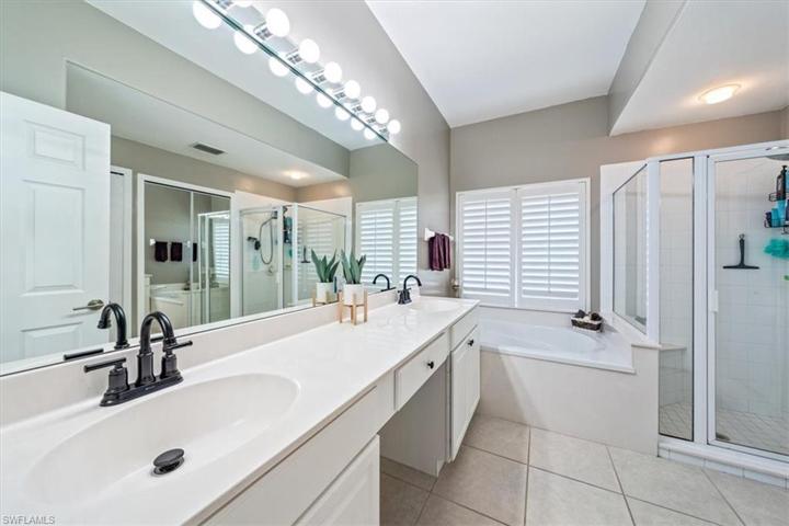 The primary sink features dual sinks, makeup/vanity seat area, built-in soaking tub with plantation shutters above for privacy, and separate shower.