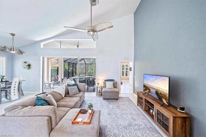 The great room enjoys views of the outdoor living area to the left, open foyer and catwalk to the right, and soaring high ceilings.