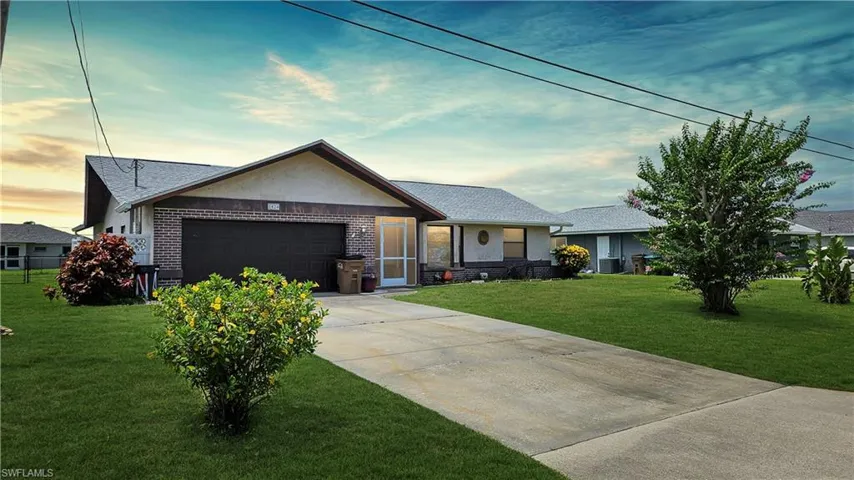Ranch-style home featuring a lawn and a garage