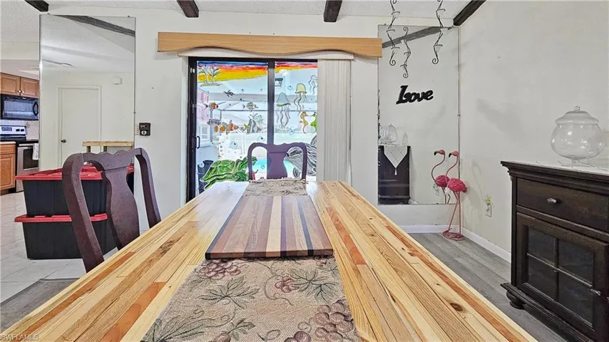 Dining space with beamed ceiling, a textured ceiling, and light hardwood / wood-style flooring
