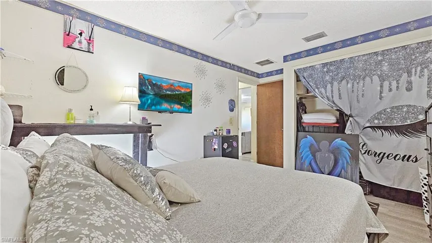 Bedroom with ceiling fan, a closet, wood-type flooring, and a textured ceiling