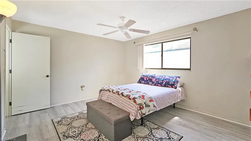 Bedroom with a textured ceiling, light wood-type flooring, and ceiling fan