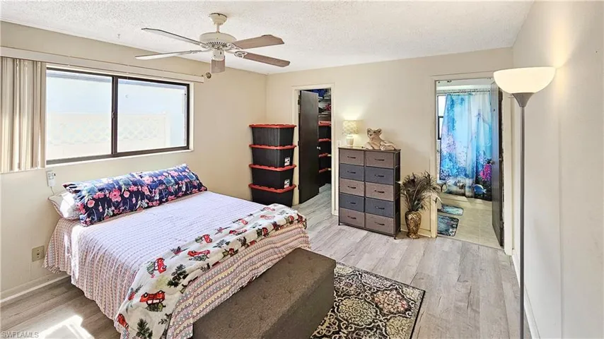 Bedroom with ceiling fan, light wood-type flooring, and a textured ceiling