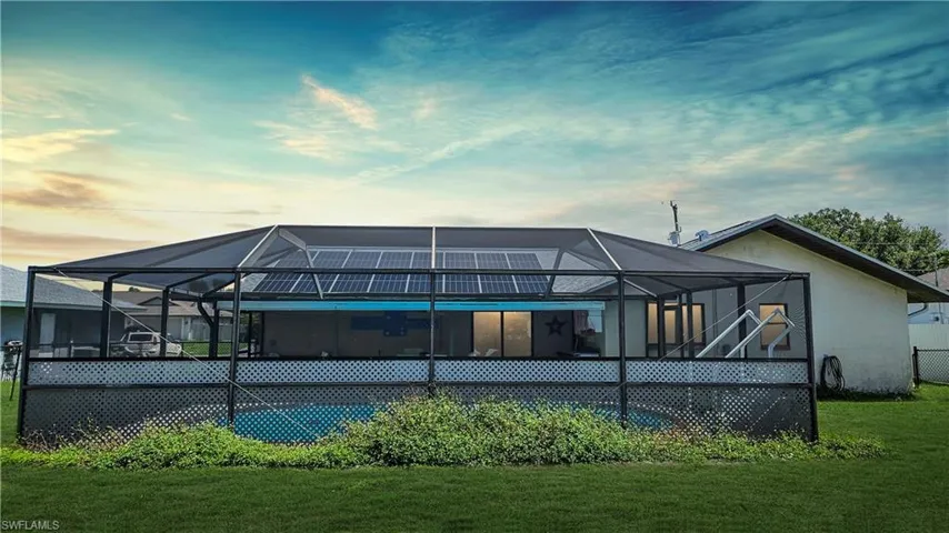 Rear view of house featuring a lawn and glass enclosure