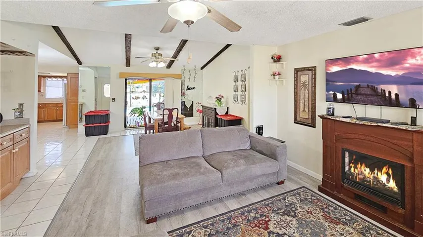 Living room featuring a textured ceiling, ceiling fan, lofted ceiling, and light tile patterned flooring
