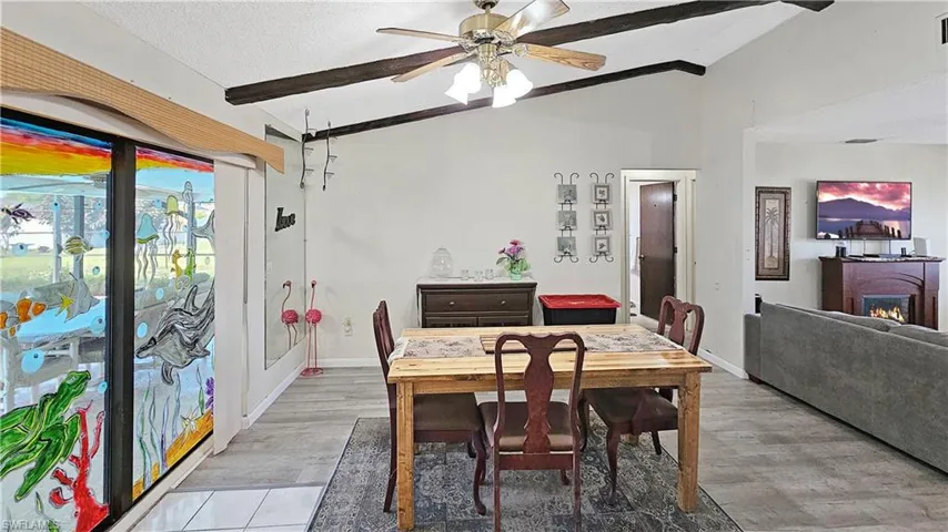 Dining space with a textured ceiling, vaulted ceiling with beams, hardwood / wood-style flooring, and ceiling fan