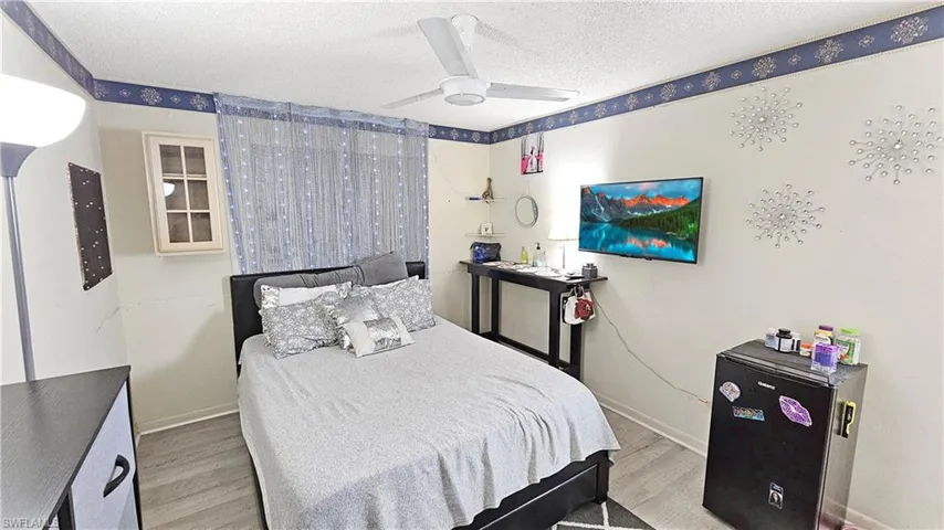 Bedroom with ceiling fan, wood-type flooring, and a textured ceiling