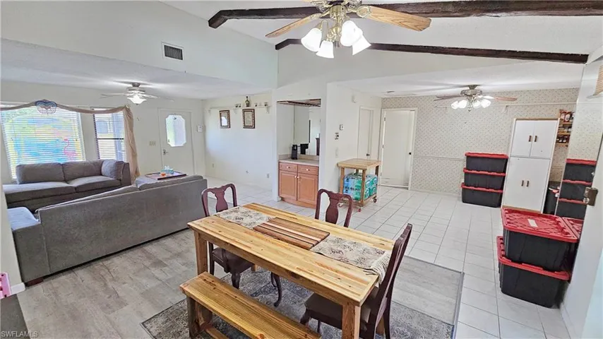 Tiled dining area featuring lofted ceiling with beams and a textured ceiling