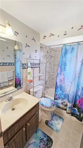 Full bathroom with tile patterned flooring, vanity, toilet, and shower / bathtub combination with curtain