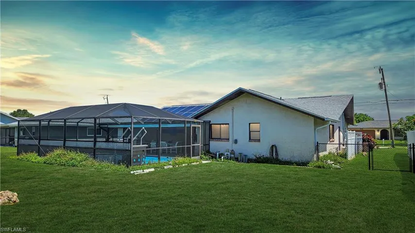 Back of property featuring a lawn and glass enclosure
