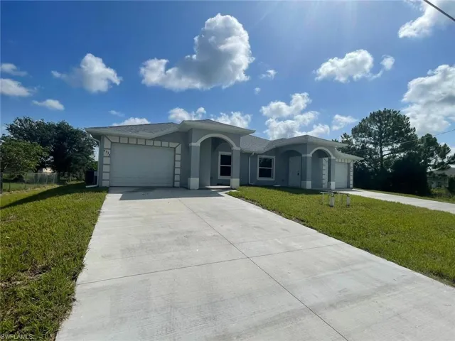 Ranch-style house with an attached garage, driveway, a front lawn, and stucco siding