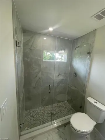 Bathroom with marble finish floors, a stall shower, and recessed lighting