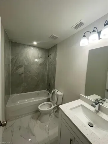 Bathroom with vanity, bathing tub / shower combination, and marble look tiles