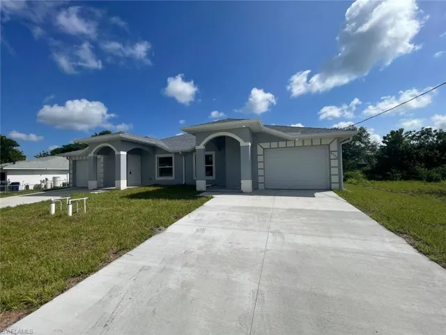Single story home with a garage, driveway, a front yard, and stucco siding