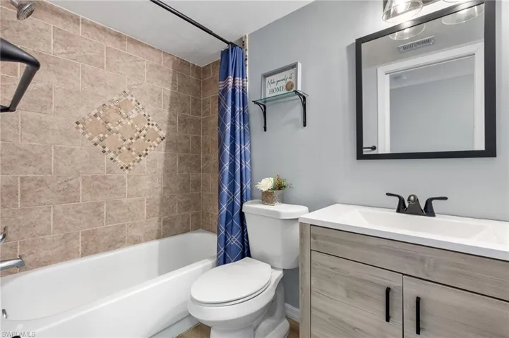 Full bathroom featuring shower / bathtub combination with curtain, vanity, and toilet