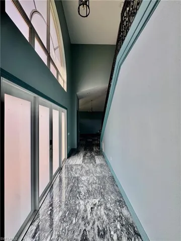 Hallway with a high ceiling, a chandelier, and marble finish floors