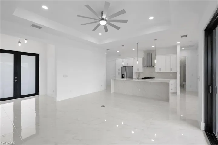 Unfurnished living room featuring french doors, a tray ceiling, and light tile patterned flooring