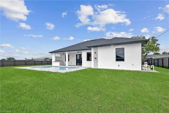 Back of property with a lawn and a fenced in pool