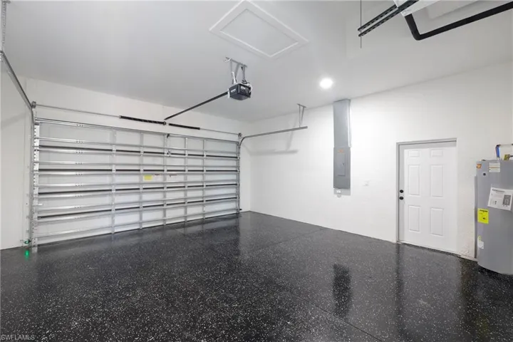 Garage featuring a garage door opener, water heater, and electric panel