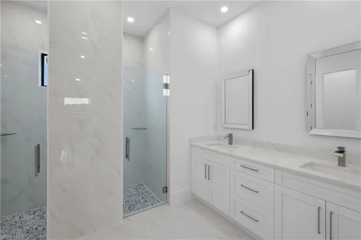 Bathroom featuring tile patterned floors, dual bowl vanity, and a shower with door