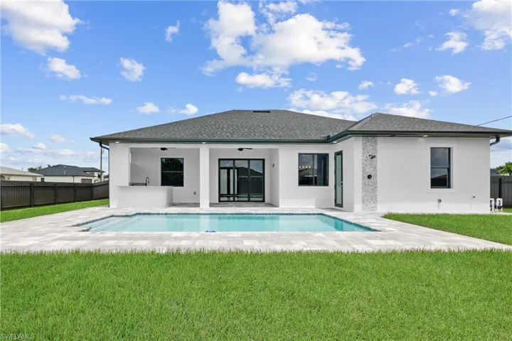 Back of property with a patio area, a lawn, and a fenced in pool