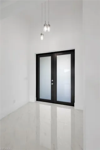 Tiled spare room with a high ceiling and french doors