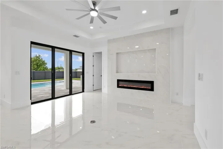Unfurnished living room featuring ceiling fan, a raised ceiling, tile patterned floors, and a fireplace