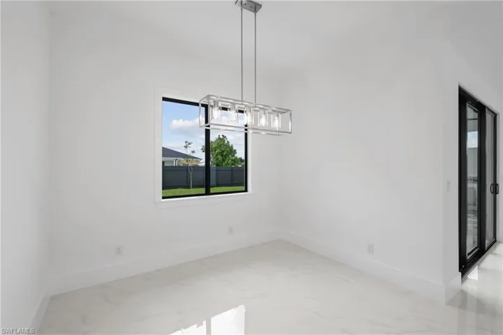Empty room with light tile patterned flooring and an inviting chandelier