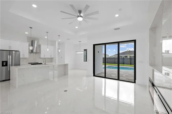 Kitchen with a tray ceiling, light tile patterned floors, range hood, and refrigerator