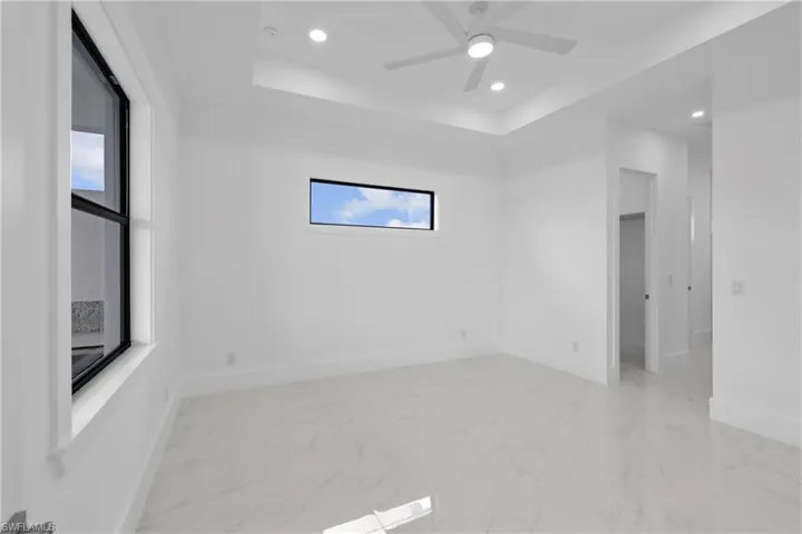 Empty room with light tile patterned floors, a raised ceiling, and ceiling fan
