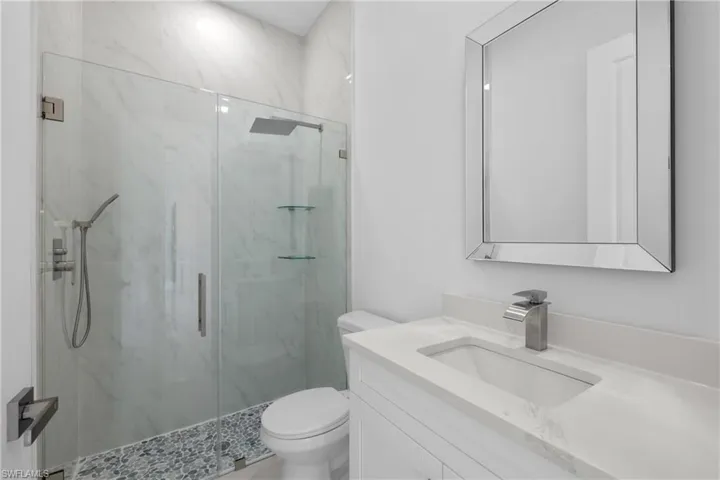 Bathroom featuring vanity, walk in shower, and toilet